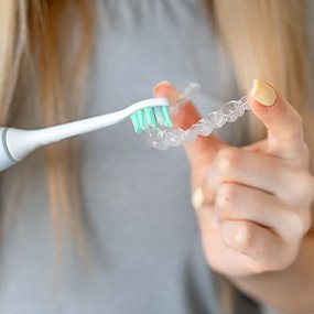 Patient using toothbrush to clean clear aligners