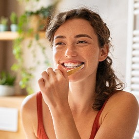 Woman smiling while brushing her teeth