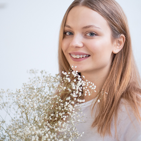 Young woman with clear ceramic braces holding a bouquet of flowers