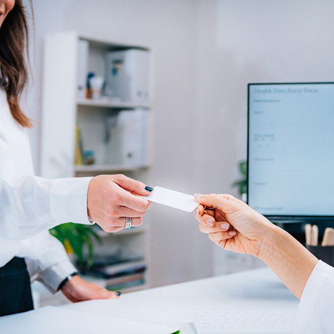 Person handing a payment card to a receptionist