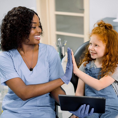 Orthodontic team member giving a high five to a young girl patient