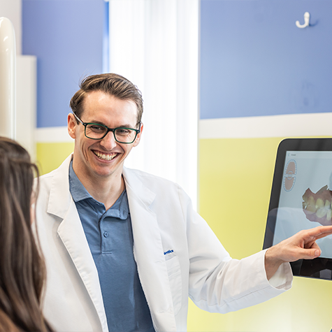 Orthodontist smiling while showing a patient an image of their teeth