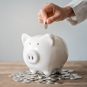 Person placing a coin into a piggy bank